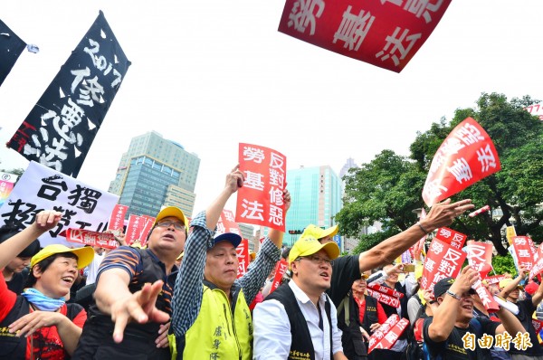 勞工團體不滿政院重啟修法，到行政院大門口前抗議，抗議群眾把手舉牌丟向行政院，表達不滿。（記者王藝菘攝）