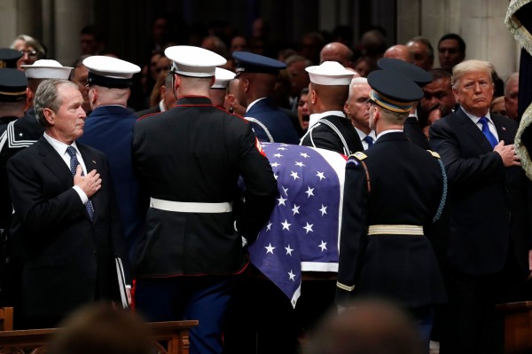 喪禮結束，老布希總統移靈時，前總統小布希（左）、現任總統川普（右）等人都起立致敬（法新社）