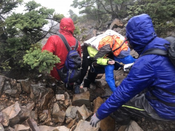 搜救人員揹著疑似高山症的梁姓女子緩慢下山。（記者李忠憲翻攝）