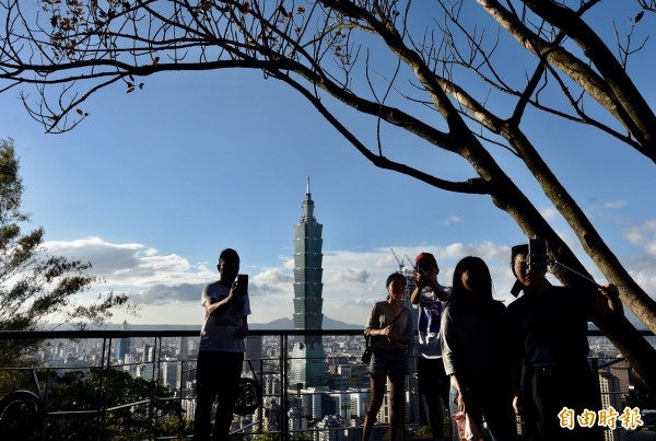 在今天公布的一項「幸福城市大調查」中,台北市蟬聯六都之首。圖為民眾趁著好天氣出遊,登象山拍台北101大樓。(資料照,記者簡榮豐攝)