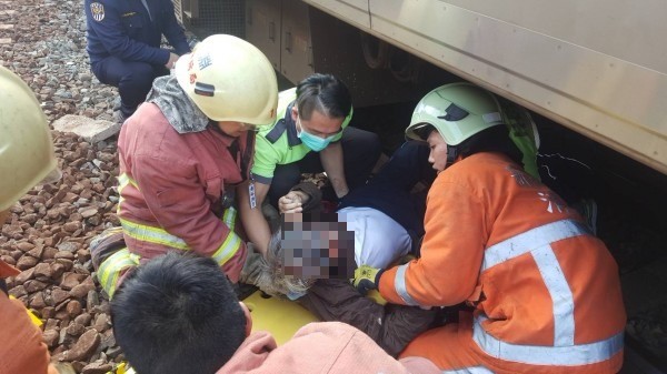 警方與消防人員將月台跳下的董姓退役軍官從列車底下拉出。（記者蔡彰盛翻攝）