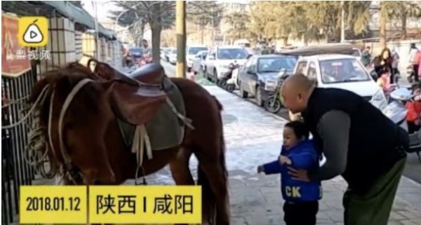 中國一名爸爸騎馬接小孩，引起圍觀。（圖劫取梨視頻）