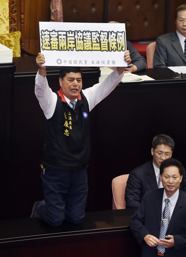 立法院新會期15日開議,朝野立委上演證所稅攻防戰,立法院長王金平召集朝野協商後宣布開會,在表決大戰中,國民黨立委張慶忠(左)跪在議事桌上呼籲速審兩岸協議監督條例。(記者廖振輝攝)
