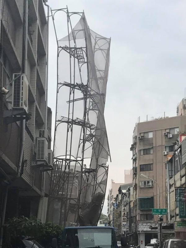 位於台中市的大樓最近在進行撤除作業，整片原應服貼建築物牆面的工地鷹架嘎然離開。（圖擷取自爆廢公社）