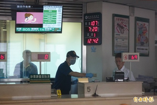 合庫沙鹿分行今天上午遭開槍搶走121萬元,警方鑑識人員現場採證。(記者廖耀東攝)