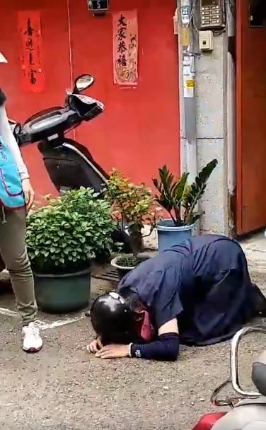 台中市一名婦人為拒絕衛生局人員入屋噴藥，不惜在自家門前磕頭下跪。（圖擷取自臉書陳榮泉）