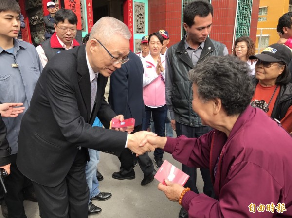 吳敦義由高雄市黨部主委韓國瑜陪同，進行高市宗教祈福之行，首站到左營城隍廟並在廟埕發送新年福袋。（記者黃良傑攝） 