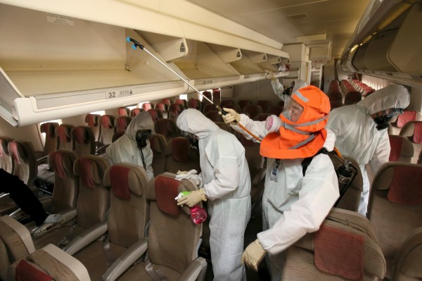 防疫人員在飛機上消毒。（路透）