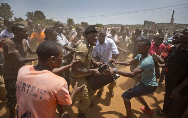 2月18日進行總統大選投票時，烏干達首都一名警察手持裝有投票用品的箱子，和民眾發生衝突，結果雙方僵持了7小時。（美聯社）