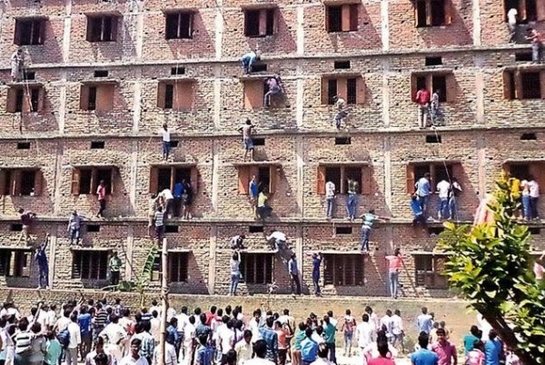 印度本月舉行大學入學考試，有數百名家長前仆後繼爬上大樓向考生遞送小抄，場景有如是在拍電影。（圖擷取自每日郵報）