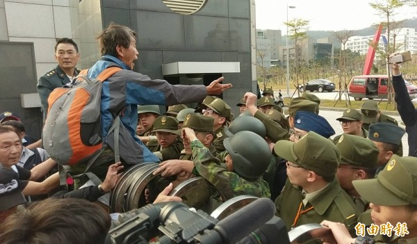 逾50名退伍軍人不滿蔡英文政府年金改革方案,聚集在國防部大門口抗議,並丟擲煙霧彈、雞蛋、撒冥紙,甚至試圖將國防部大門搖倒。(記者方賓照攝)