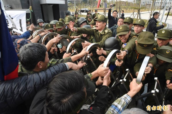 逾50名退伍軍人不滿蔡英文政府年金改革方案,聚集在國防部大門口抗議,並丟擲煙霧彈、雞蛋、撒冥紙,甚至試圖將國防部大門搖倒。(記者方賓照攝)