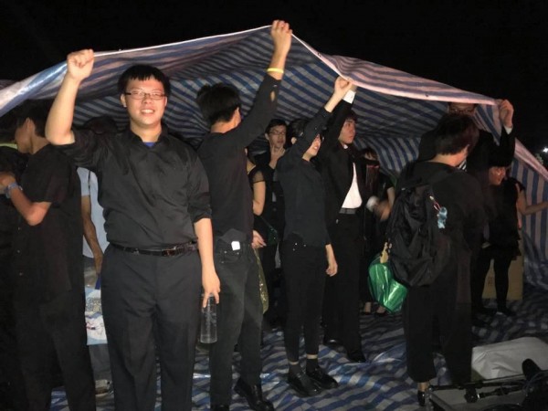 音樂家們唯一能躲雨的地方只是一塊帆布,而且還要自己撐起。(圖由馮楚軒提供)