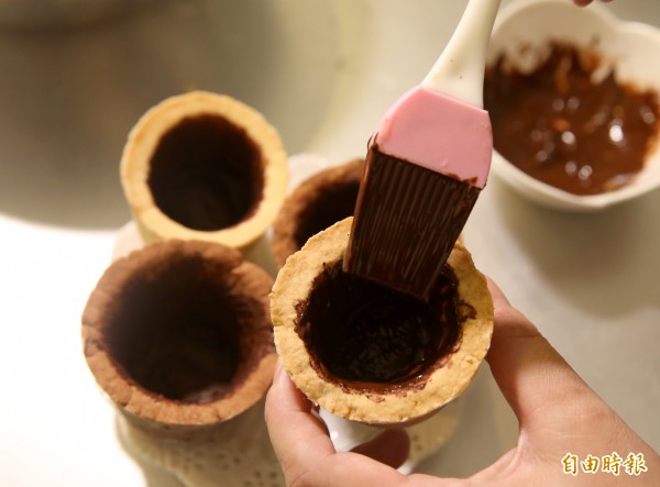 在餅乾杯子內層塗上熔化的巧克力，待乾後可避免餅乾杯子直接接觸飲品而軟化。（記者臺大翔攝） 