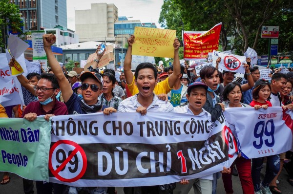 越南人民今聚集在各大城市,手拿標語布條遊行抗議「經濟特區法草案」。(法新社)