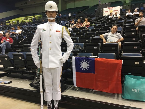 蘇祈麟赴美參加「世界儀隊錦標賽」，與國旗合影。（中央社）