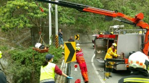 丁男撞擊新社區橋樑護欄後翻落四公尺高橋面，救難人員出動吊掛機具將他救起。（記者李忠憲翻攝）