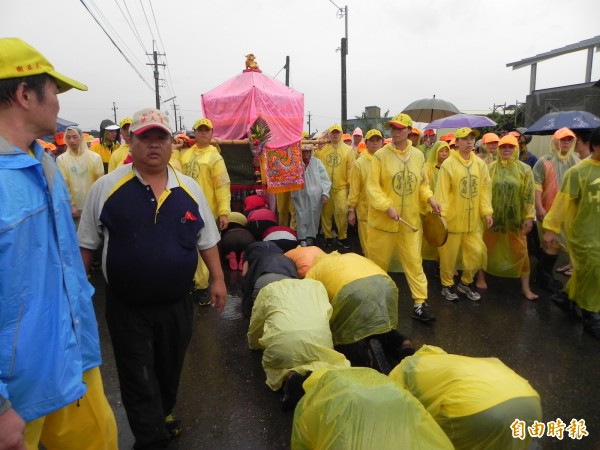 白沙屯媽進香,信徒顧不得大雨爭相跪地鑽轎腳。(資料照,記者廖淑玲攝)