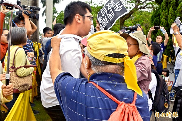 頭戴黃帽、藍上衣的老伯抓著潘姓同學(白衣者)的後衣領,最後致其受傷。(記者吳柏軒攝) 頭戴黃帽、藍上衣的老伯抓著潘姓同學(白衣者)的後衣領,最後致其受傷。(記者吳柏軒攝)