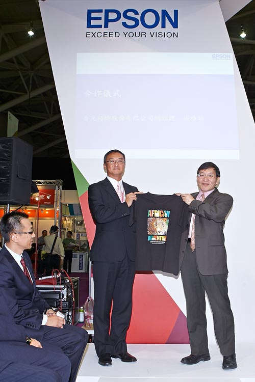 發表會上「台元紡織」戚維功總經理現場致贈「台灣愛普生」陳維鈞副總經理精美的 T 恤和購物袋,是以搭載 Epson 專業核心技術 F2000 織品直噴印刷機及台元紡織優質布料印製而成,見證雙方合作。