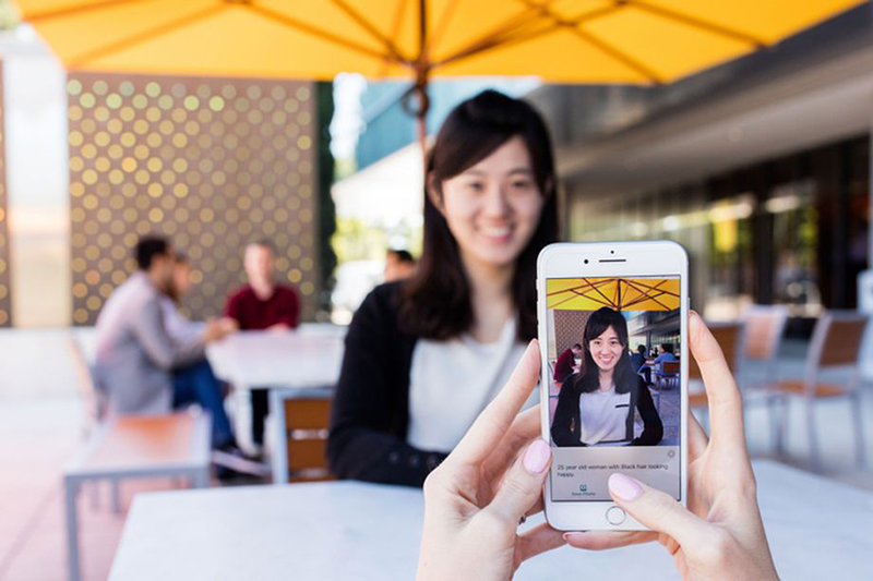 只需要在 iPhone 上開啟 Seeing AI,並將鏡頭對準目標,Seeing AI 就會自動分析人物,並且顯示年齡、外貌特徵。(圖片來源/The Verge)