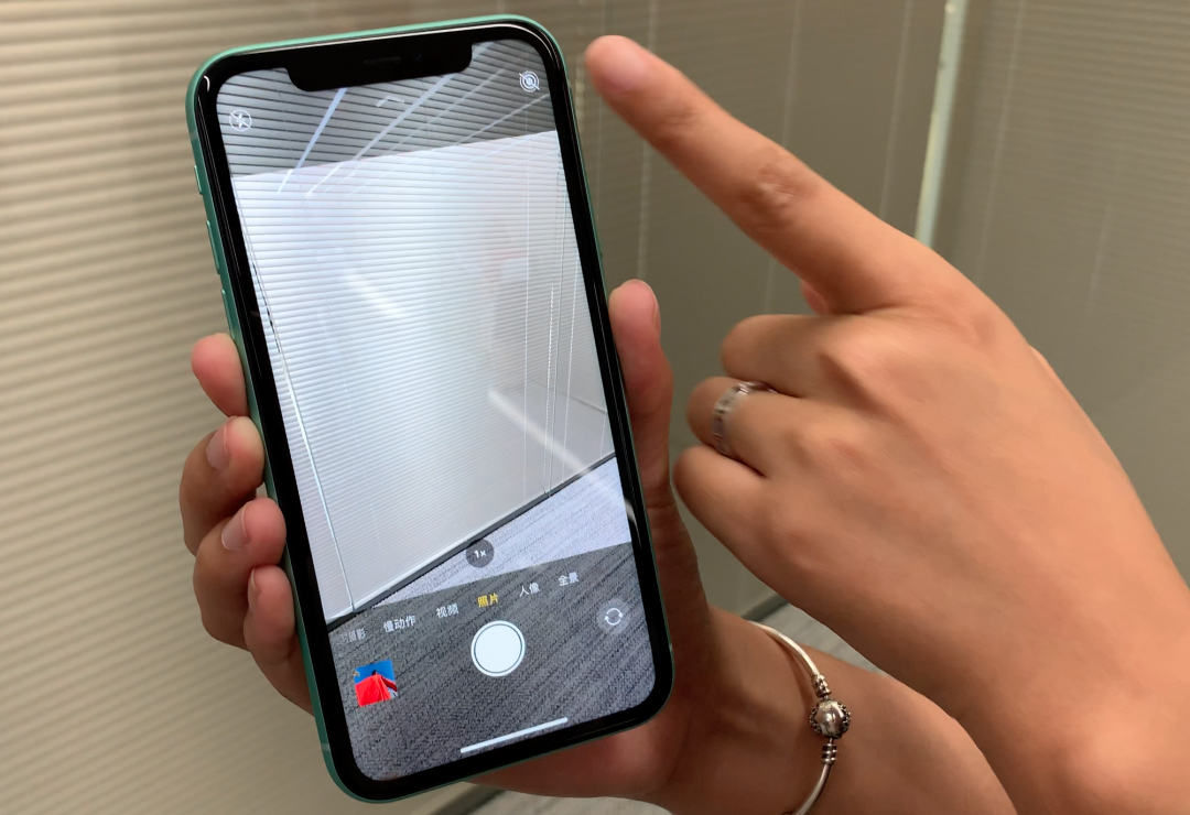 iPhone 11 系列的相機因應新增超廣角鏡,相機 App 中上下兩端原為黑底的部份都改為半透明,讓用戶在使用一般廣角鏡拍攝時,還是能見到由超廣角鏡頭呈現、超出一般取景窗的視野內容(圖/記者黃敬淳攝)