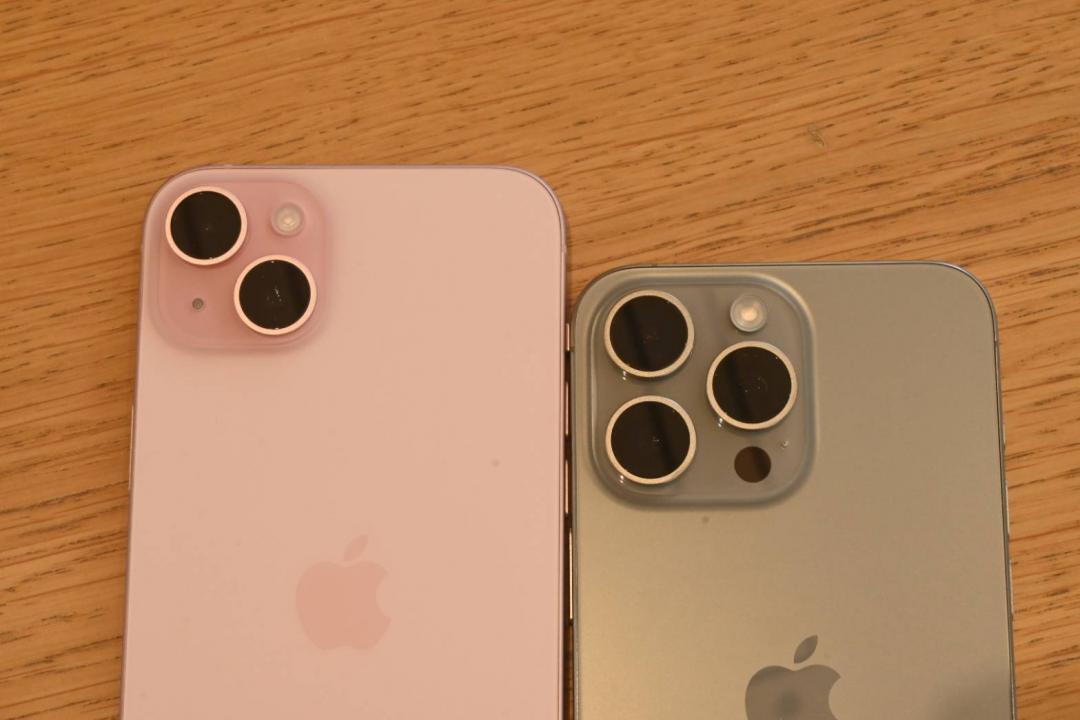 左為 iPhone 15 Plus 粉紅色，右為 iPhone 15 Pro Max 原色，同樣的螢幕尺寸，鏡頭模組差異明顯。（圖／記者黃肇祥攝）