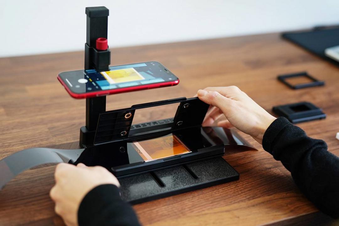 把手機放置在掃描器的上方固定支架,再把底片放進底端的固定架,即可進行翻拍掃描。