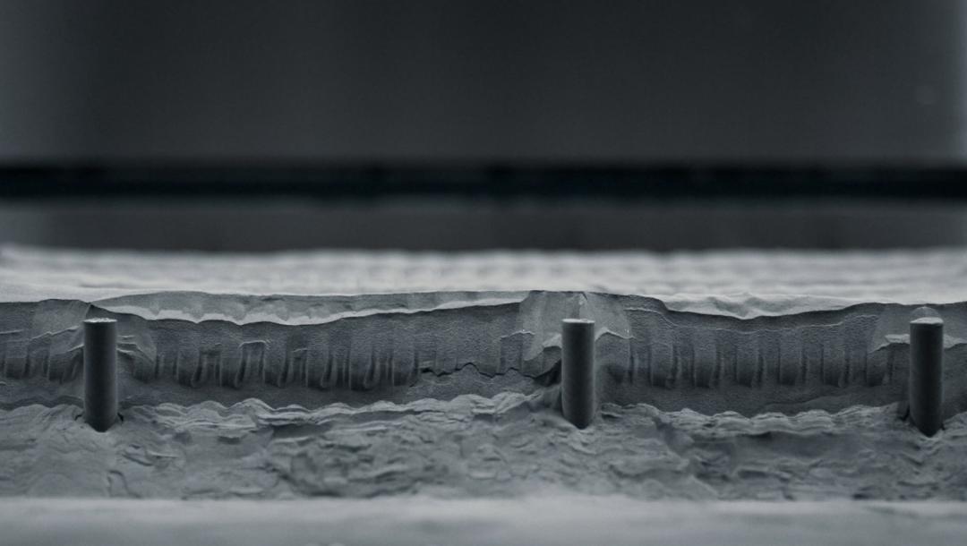 列印機完成作業後，操作人員會將多餘的粉末從成形板上以真空方式吸除，這個步驟稱為粗略除粉。（圖／蘋果）