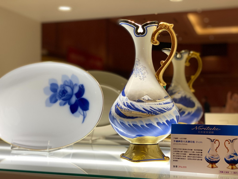右為Noritake「手繪神奈川浪濤花瓶」，展現江戶時代風華的浮世繪，取材風景繪大師葛飾北齋《富嶽三十六景》的經典畫作〈神奈川沖浪裏〉，畫師細膩刻畫充滿張力的神奈川浪濤，將西方造型花器與日本浮世繪結合，呈現出具現代感的藝術裝飾，左為OKURA「藍玫瑰橢圓盤」，呈現大倉陶園經典的藍玫瑰紋樣。 （旺代提供）