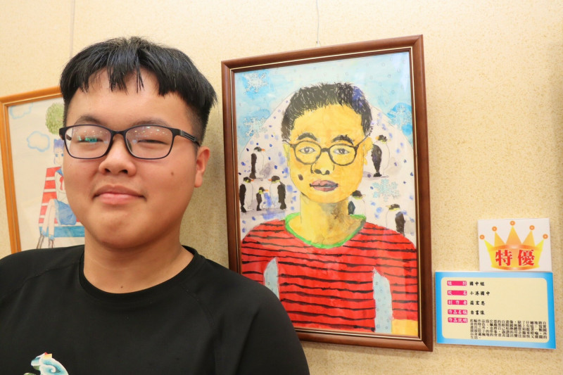 小港國中莊宏恩同學獲國中組特優,作品為〈自畫像〉,以詼諧創作將自己的臉上的痣放大,並用企鵝來暗喻自己,再以身處極地的背景,表達出嚮往涼快與廣闊的生活。(高雄市教育局提供)