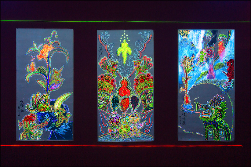 李俊陽創作的展間，散發劇場燈光效果的迷幻螢光隧道，掛滿配色大膽、描繪傳統民俗意象的繪畫，其中藏著一隻霓虹龍。（北美館提供）