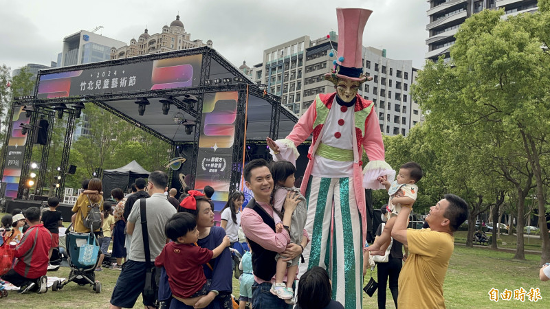 竹北市長鄭朝方（中）、竹北市代會主席林啟賢（右著黃衣者）一起抱起身旁的小朋友們跟耍雜耍的小丑演員互動。（記者黃美珠攝）