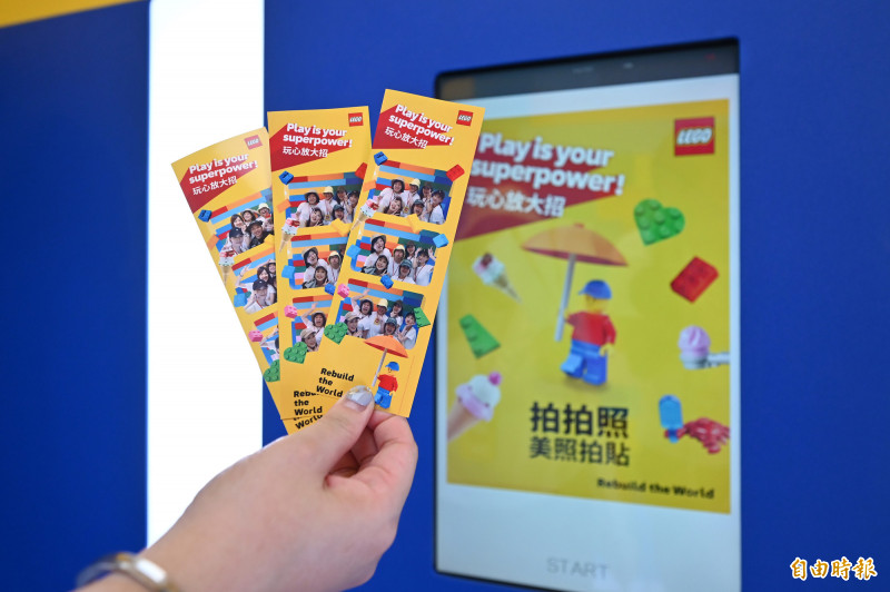 美美照拍貼區，大小朋友進入巨大樂高積木箱，裡頭可以將組好的樂高積木帶來一同合照，之後機器將會洗出照片作為紀念。（記者李惠洲攝）