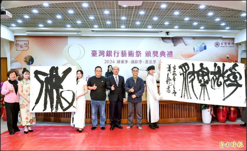書法家於同生（左4）與蕭世瓊（右2）現場揮毫寫成的字，與臺銀副總經理戴士原（右3）合影。（記者王文麟攝）