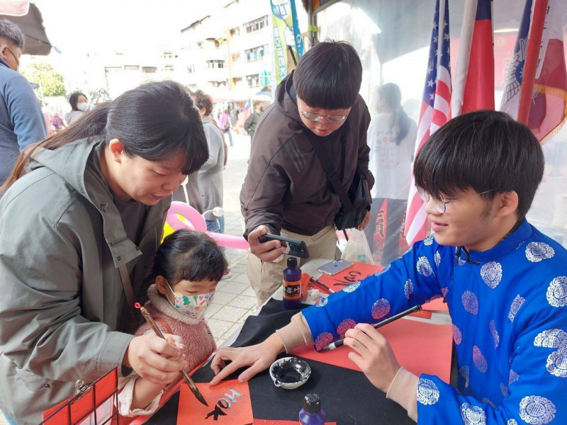 越南學生林俊義（右）與參加民眾互動，教寫台羅台語文春聯。（南市文化局提供）