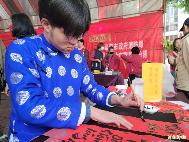 成大台文系大三同學、越南籍林俊義，今天穿著越南傳統服飾，在開基玉皇宮廟埕現場揮毫。（記者王姝琇攝）