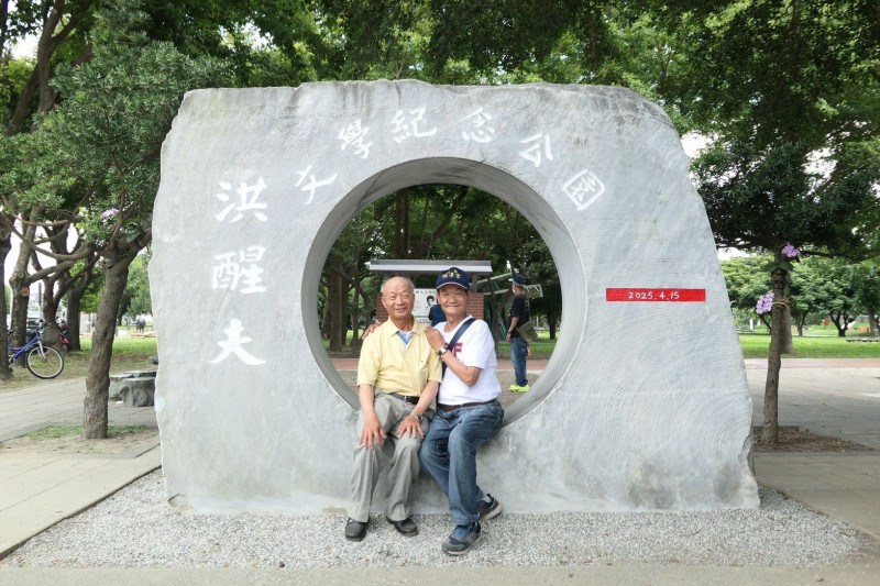 洪醒夫胞弟洪媽量（左），及四弟洪漢文（右）主題石碑前合影。（彰化縣文化局提供）