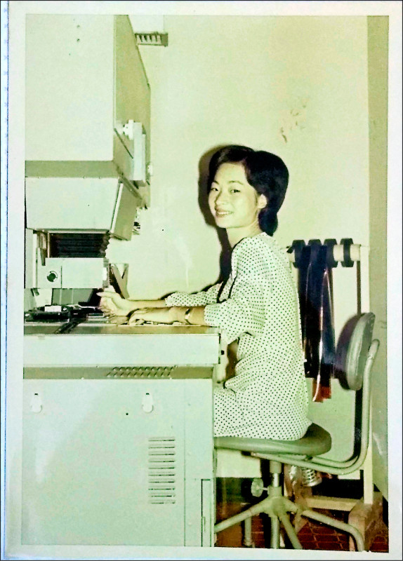 廖瞇的媽媽阿美在自動放相機台前打相片，右手邊吊的是底片。（廖瞇提供）