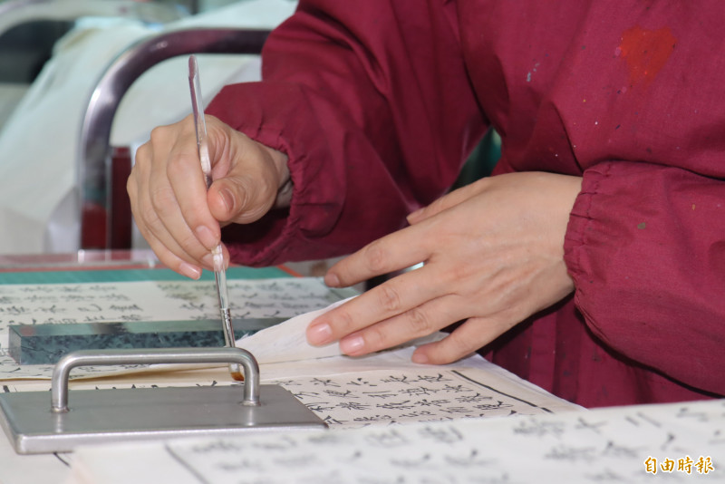 修復《法華經》難度高，因為經書讀到破損或頁面斷裂，證嚴就會自行用膠帶、紙片黏貼補合，修復非常不易。（記者翁聿煌攝）