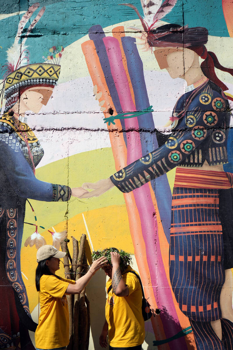  屏東縣來義鄉望嘉、文樂、喜樂發發吾等部落，本週展開一年一度收穫祭，鄉公所同時辦理情柴文化祭「送情柴」體驗，由男性參與者肩扛象徵愛意情柴，贈給心儀對象，女方則為男方戴上花圈。（中央社提供）