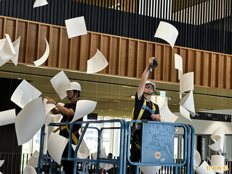 施工人員利用移動式升降梯，一片一片以人工清潔「紙張」及鋼索。（記者劉婉君攝）