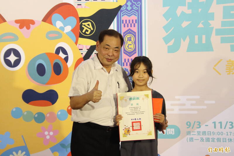 新竹縣副縣長陳見賢頒獎給彩繪神豬優選創作者、枋寮國小學童劉鎔慈。（記者黃美珠攝）