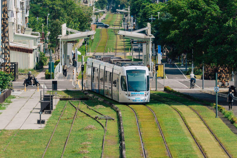 書展列車穿行城市街景，與人群共織移動風景。（高市圖提供）