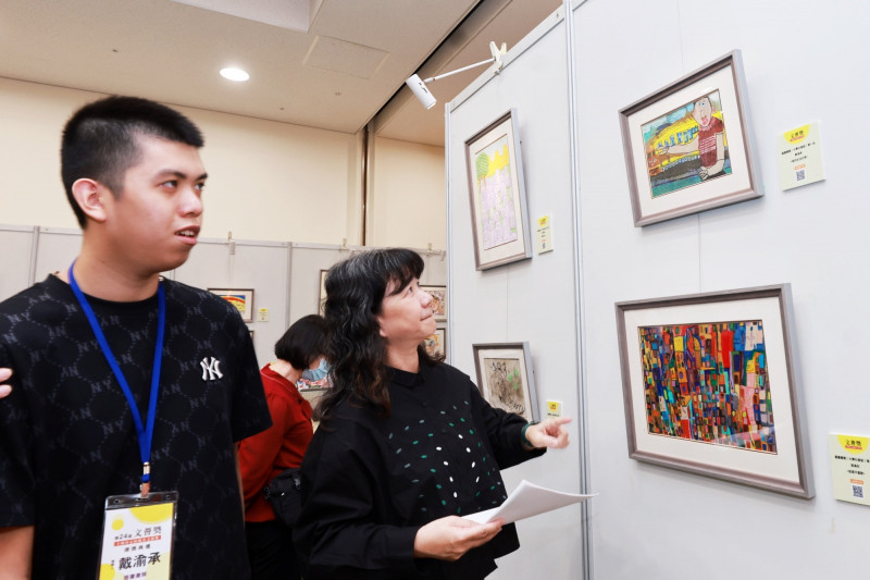 文化部政務次長李靜慧欣賞文薈獎「圖畫書類大專社會組」第1名戴渝承（左）作品。（文化部提供）