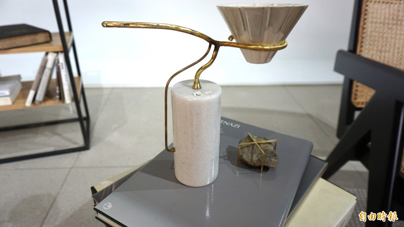 王旋設計的咖啡濾器支架有著優美弧線，與白色圓柱體底座形成比例平衡，支撐著吳偉丞設計的簡約陶製濾杯。（記者董柏廷攝）