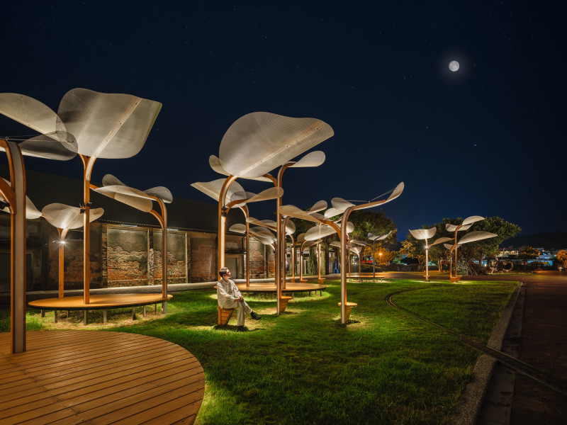 民眾在夏日夜晚坐在巨型植物結構下的木質長椅休憩，讓原本開放的草地擁有更多重新被感知的彈性。（范承宗提供）