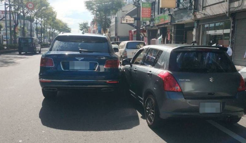 一輛千萬賓利轎車，今天早上在大里國光路撞上併排停車的自小客車，車子的輪子還卡住動彈不得。（記者陳建志翻攝）