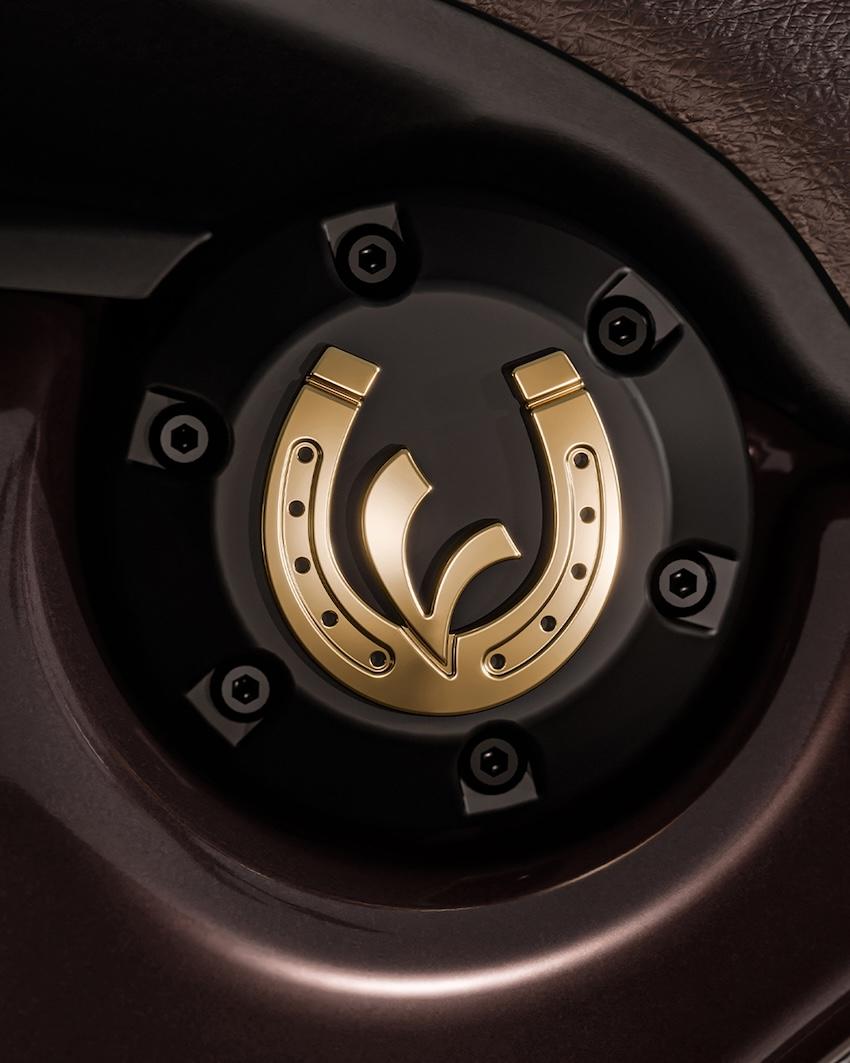 座墊下方一枚金色的馬蹄鐵，環繞著 Vespa 的「V」字標誌。