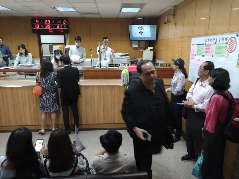 元利老董林敏徐派出小兒子林弘人（中間西裝者）與副總經理吳麗謹（中間黑白點洋裝者）到台北地院民事執行處投標盯哨。龍巖代表（右黑衣持手機者）失望離去。（記者吳政峰攝）